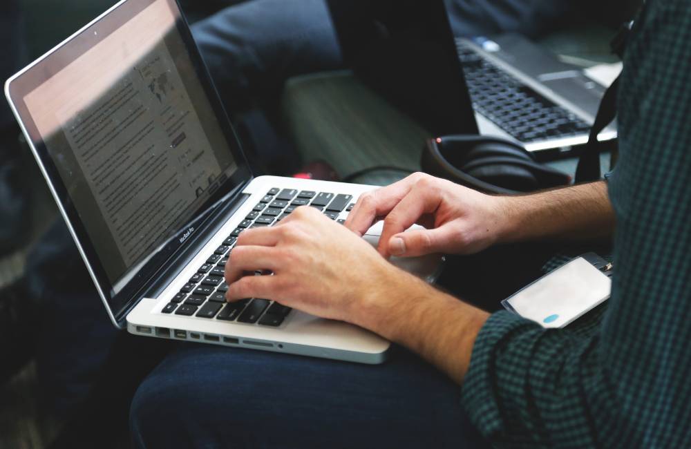 カジュアルな服装でノートパソコンを操作する人の手元(日常使いや仕事での活用シーン)