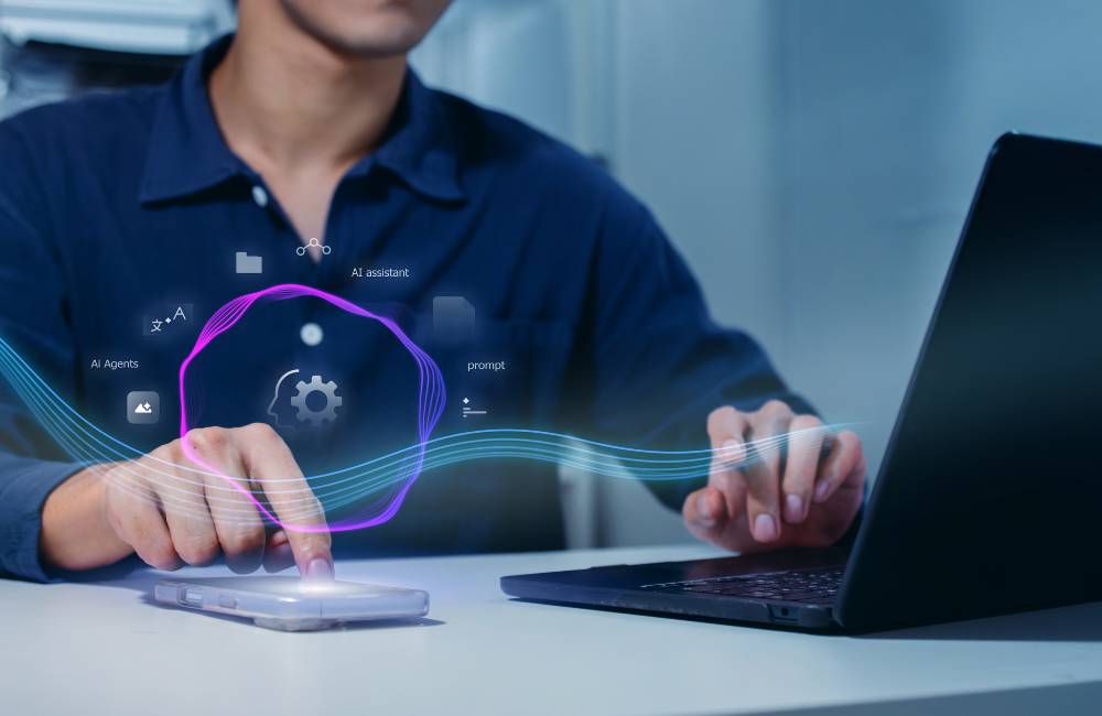 ノートパソコンを操作する人の周りに、システムやサポートを象徴するアイコンが浮かび上がるイメージ