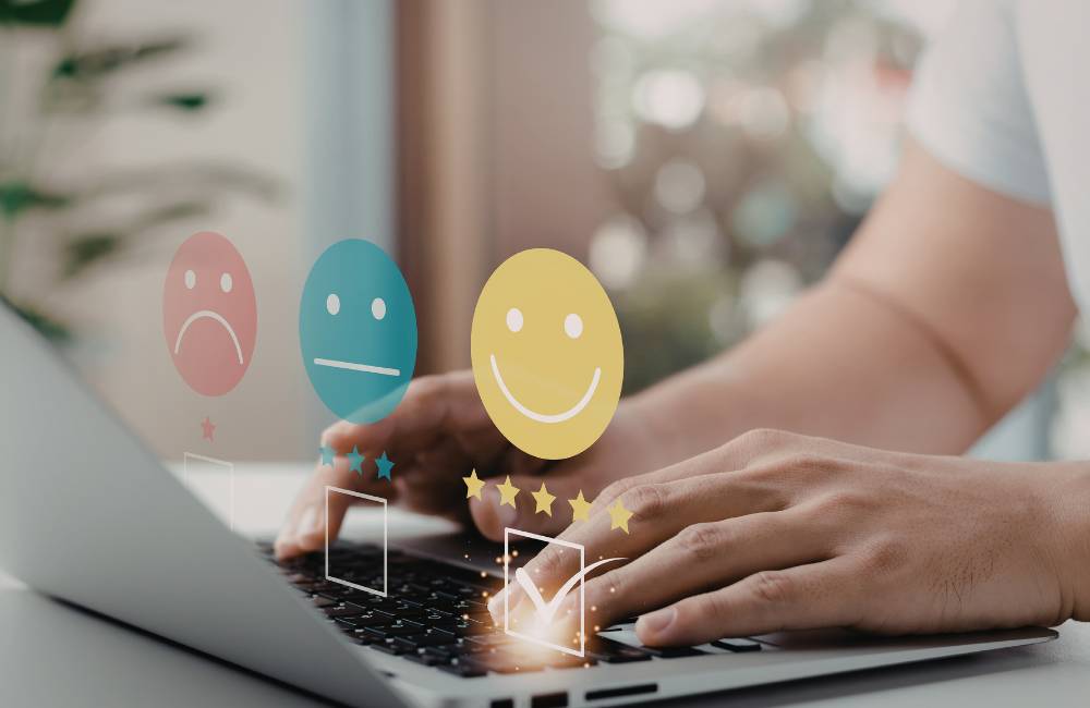 ノートパソコンのキーボード上で、笑顔の評価アイコンを選択する様子(利用者の満足度やリアルな声を表現)