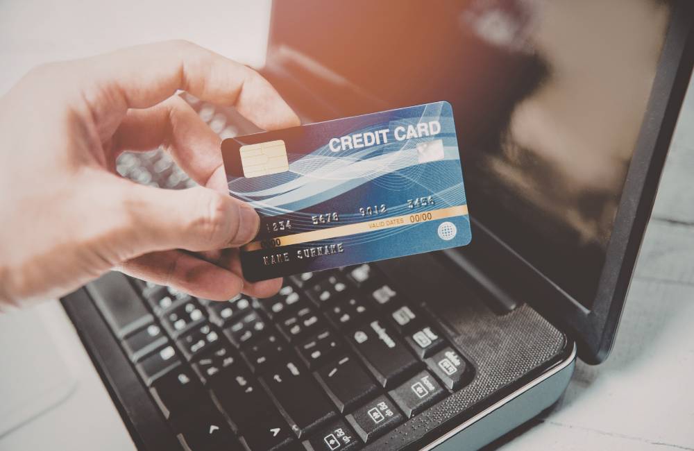 ノートパソコンの前でクレジットカードを持ち、決済の準備をしている様子(お買い得な購入チャンスを表現)