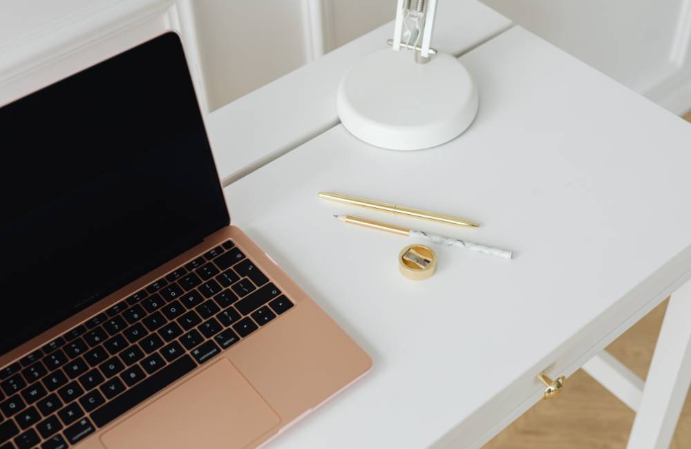 白いデスクの上に置かれたスタイリッシュなノートパソコンと文房具(高品質なPCを求めるライフスタイルを表現)