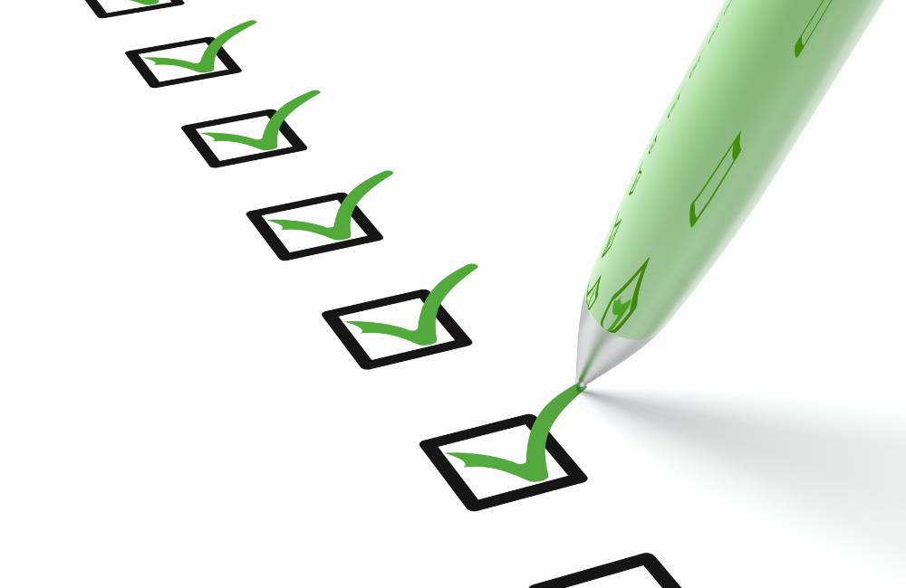 白い紙に並んだチェックボックスに、緑色のペンで次々とチェックマークが入れられていく様子。購入前に確認すべき項目を一つずつクリアしていくイメージ。