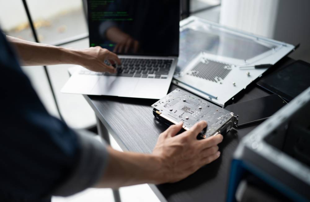 作業台の上でバラバラになったPCパーツやグラフィックボードを手にする様子。個人売買やオークションなど、保証がなく専門知識が必要になるリスクを表現。