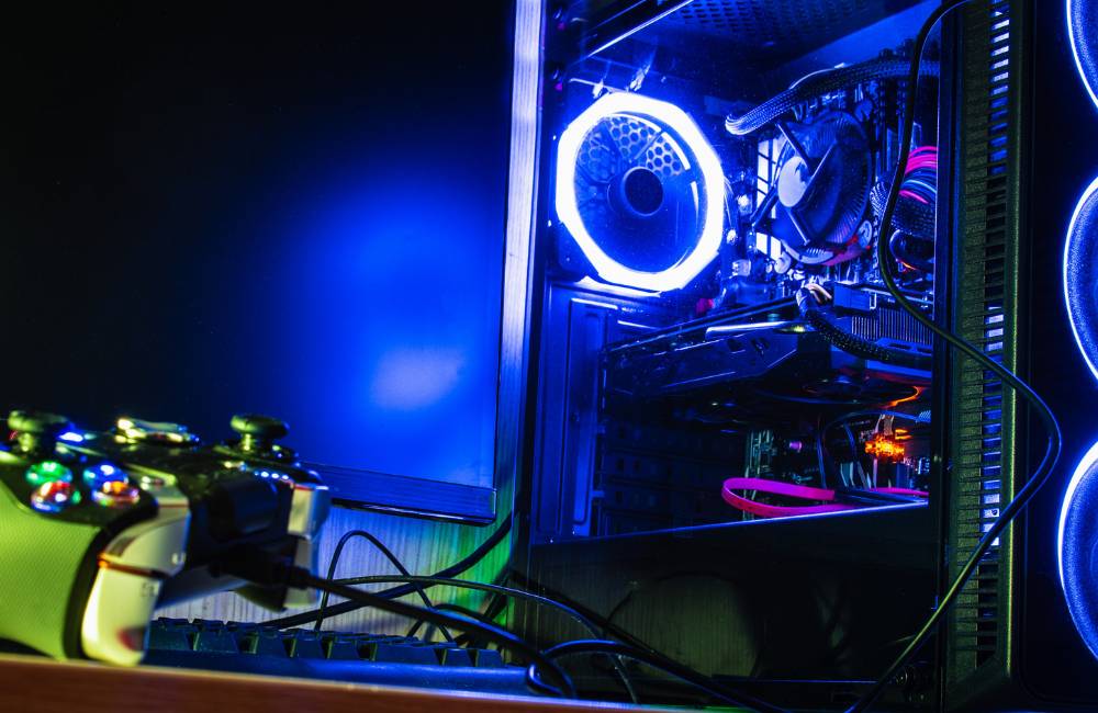 青く光るLEDファンを搭載した自作風デスクトップPCの内部と、傍らに置かれたゲームコントローラー。高いカスタマイズ性を誇るBTOメーカー各社の技術力を象徴しています.