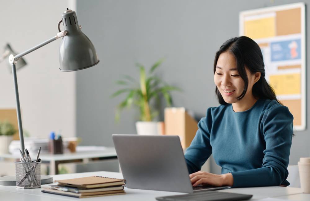 自宅でDELLの中古ノートパソコンを快適に使い、明るい表情でオンライン作業や学習に取り組む女性