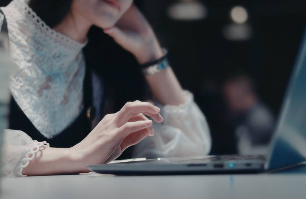 柔らかな光の中でノートパソコンを操作する女性の手元。記事の内容を振り返り、納得して検討を終える穏やかな雰囲気。