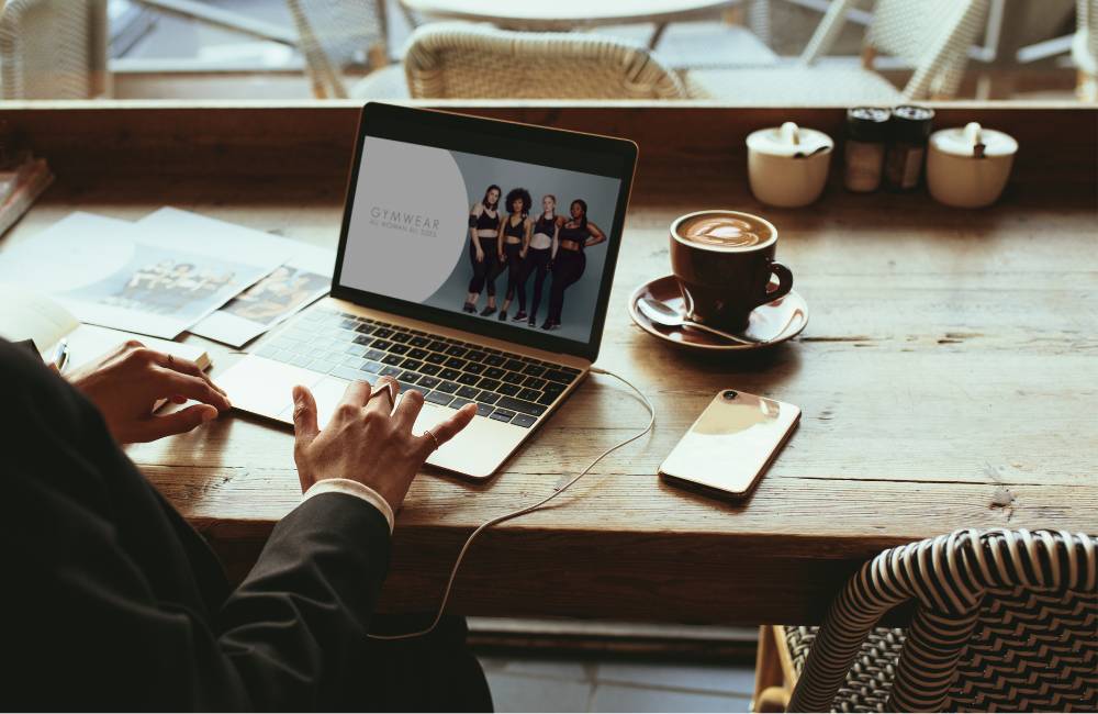 カフェのテラス席でノートパソコンを開き、コーヒーを傍らに置いて作業する様子。モバイルワークや多様なライフスタイルへの適応を表現。