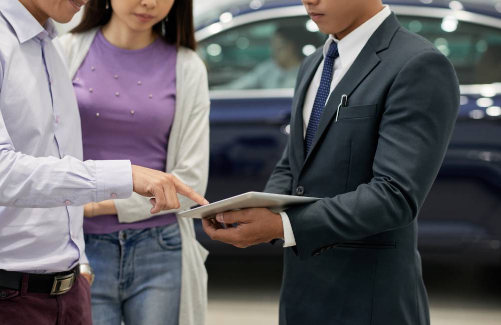 接客スタッフがタブレットを手に、顧客へ商品の説明を行っている様子。信頼できる店舗での購入相談をイメージ。