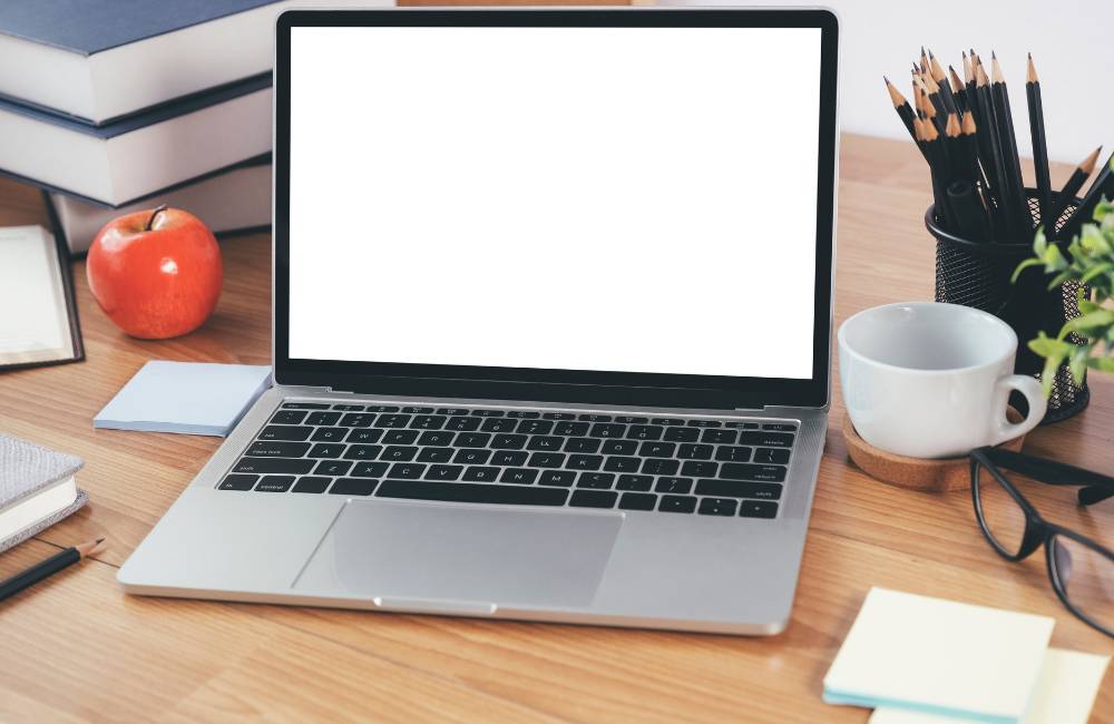 明るいデスクに置かれた清潔感のあるノートパソコンと文房具（富士通パソコンの信頼性と使いやすさをイメージ）