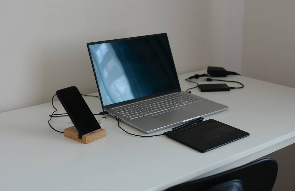 パソコンの側面にスマートフォンやペンタブレットがケーブルで繋がれている様子