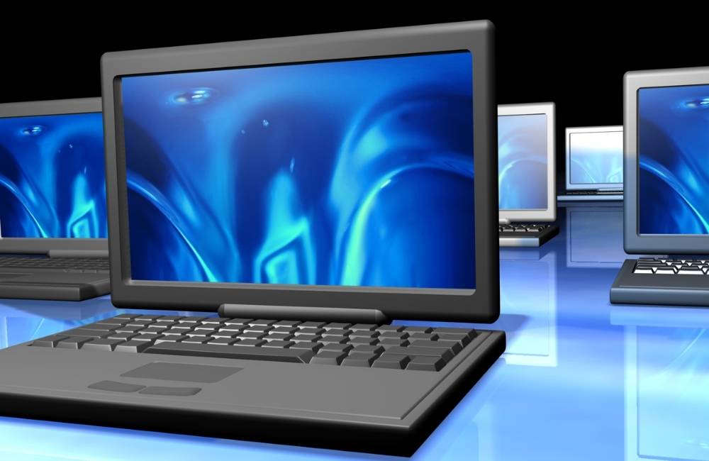青い光の中に複数のノートパソコンが整然と並んでいるデジタルイメージ