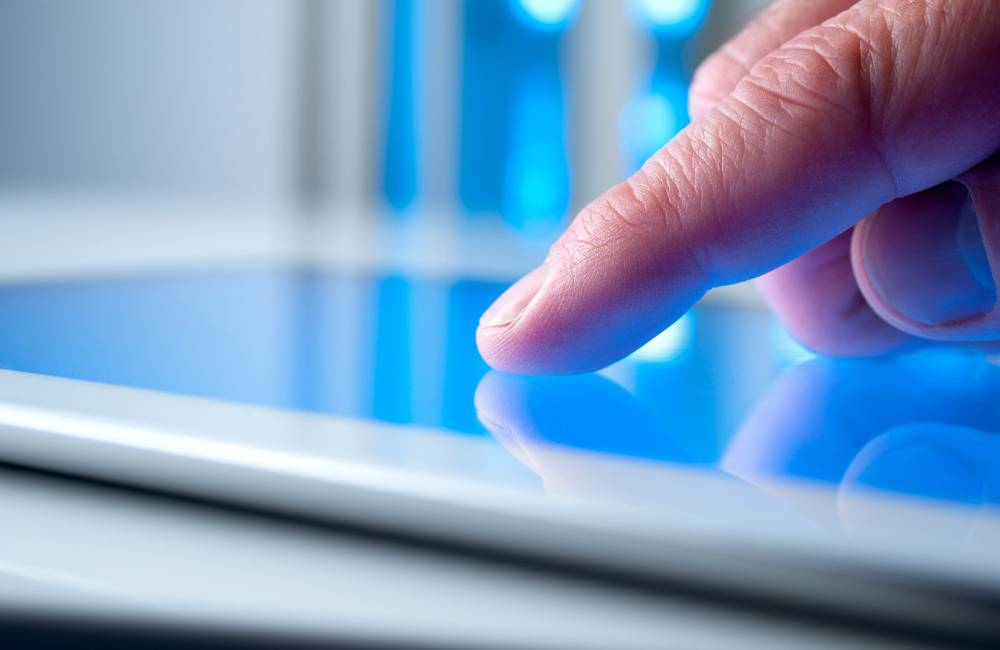 タブレットの液晶画面を指でタッチして操作し、反応や汚れを確かめている様子