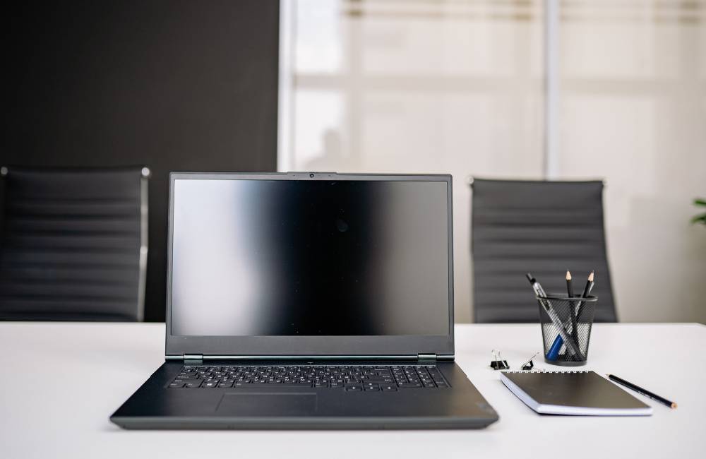 清潔感のあるオフィスのデスクに広げられたノートパソコンと、横に置かれた筆記用具がメンテナンスの準備を整えたような整然とした様子
