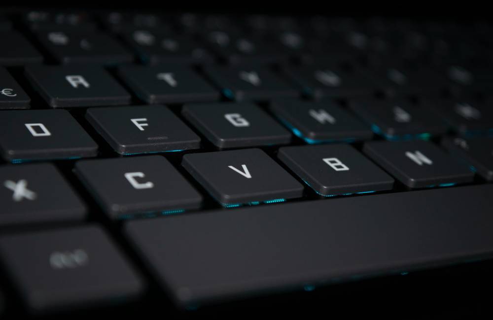 暗い背景の中で、ほのかなバックライトが点灯したThinkPad特유の凹凸のあるキーキャップが際立つキーボードの接写写真