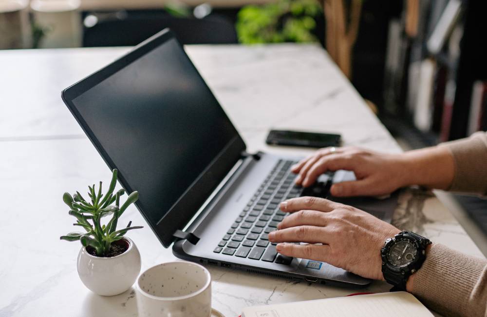 デスクでノートパソコンのキーボードをタイピングする手元のアップ（VAIOの傾斜キーボード）