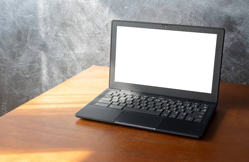 木目調のデスクに置かれた清潔感のあるノートパソコン。状態の良さを客観的に示す構図。