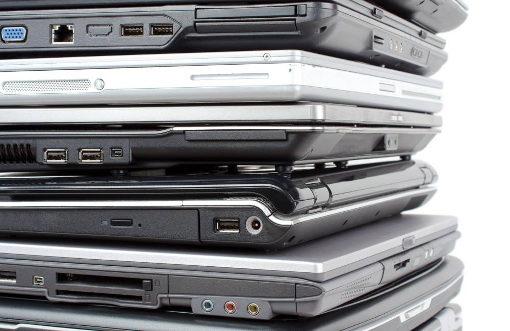大量に積み上げられた多種多様な中古ノートパソコンの山