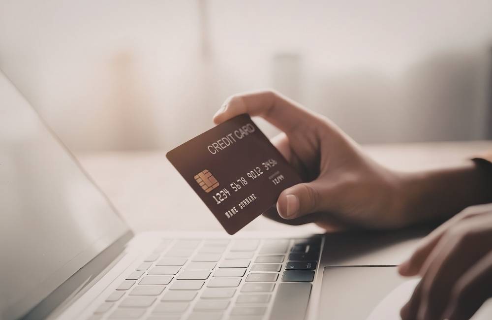 白いノートパソコンのキーボードの横に置かれた、シルバーのミニチュアショッピングカート。