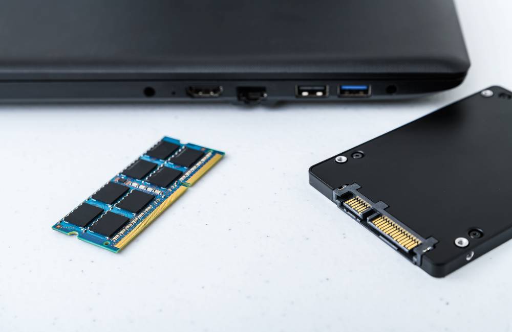 ノートパソコンの横に並べられた新品のメモリとSSDのパーツ。内部部品がリフレッシュされている様子