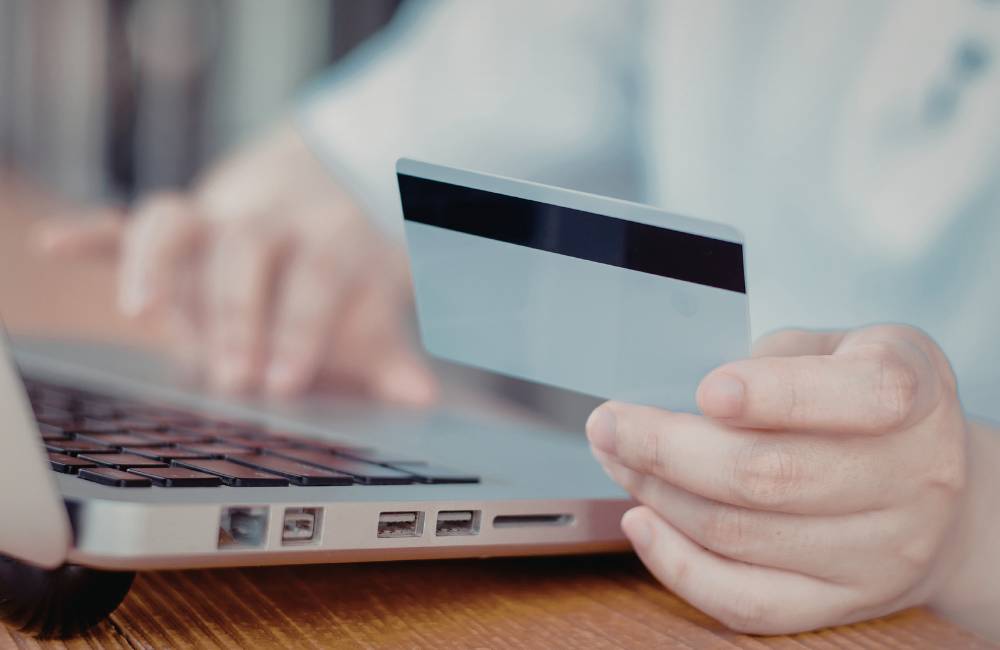 ノートパソコンを操作しながらクレジットカードを手元に持つ、オンライン決済や購入のイメージ
