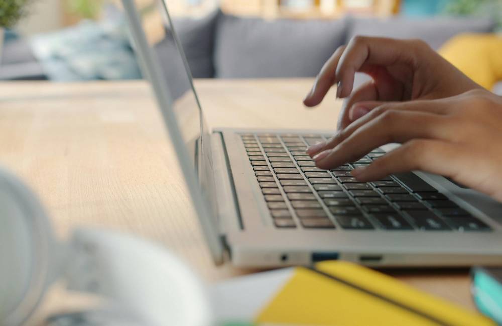 明るい室内でノートパソコンのキーボードを軽快にタイピングし、作業が順調に進んでいる様子