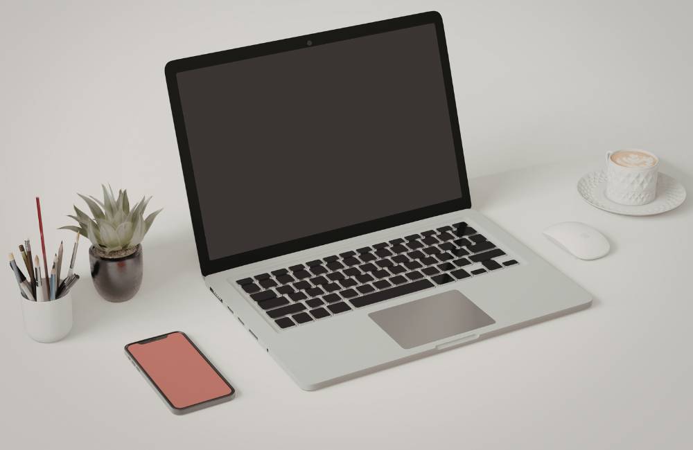 整理整頓された白いデスクに置かれたノートパソコンとコーヒー。納得のいく買い物を終えた後の清々しいイメージ