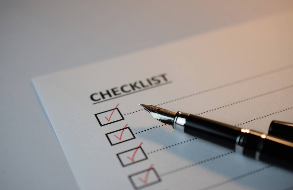 紙のチェックリストに万年筆でチェックを入れ、スペックや状態に漏れがないか確認している手元