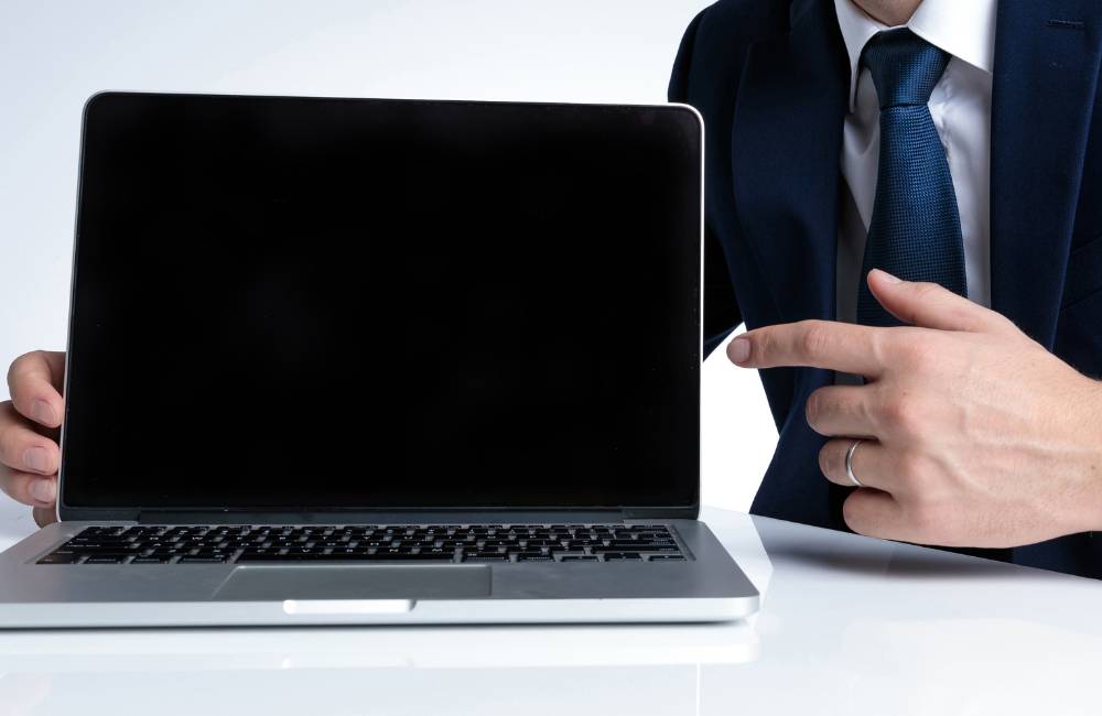 スーツを着た男性がノートパソコンの画面を指差し、おすすめの専門店を紹介している様子